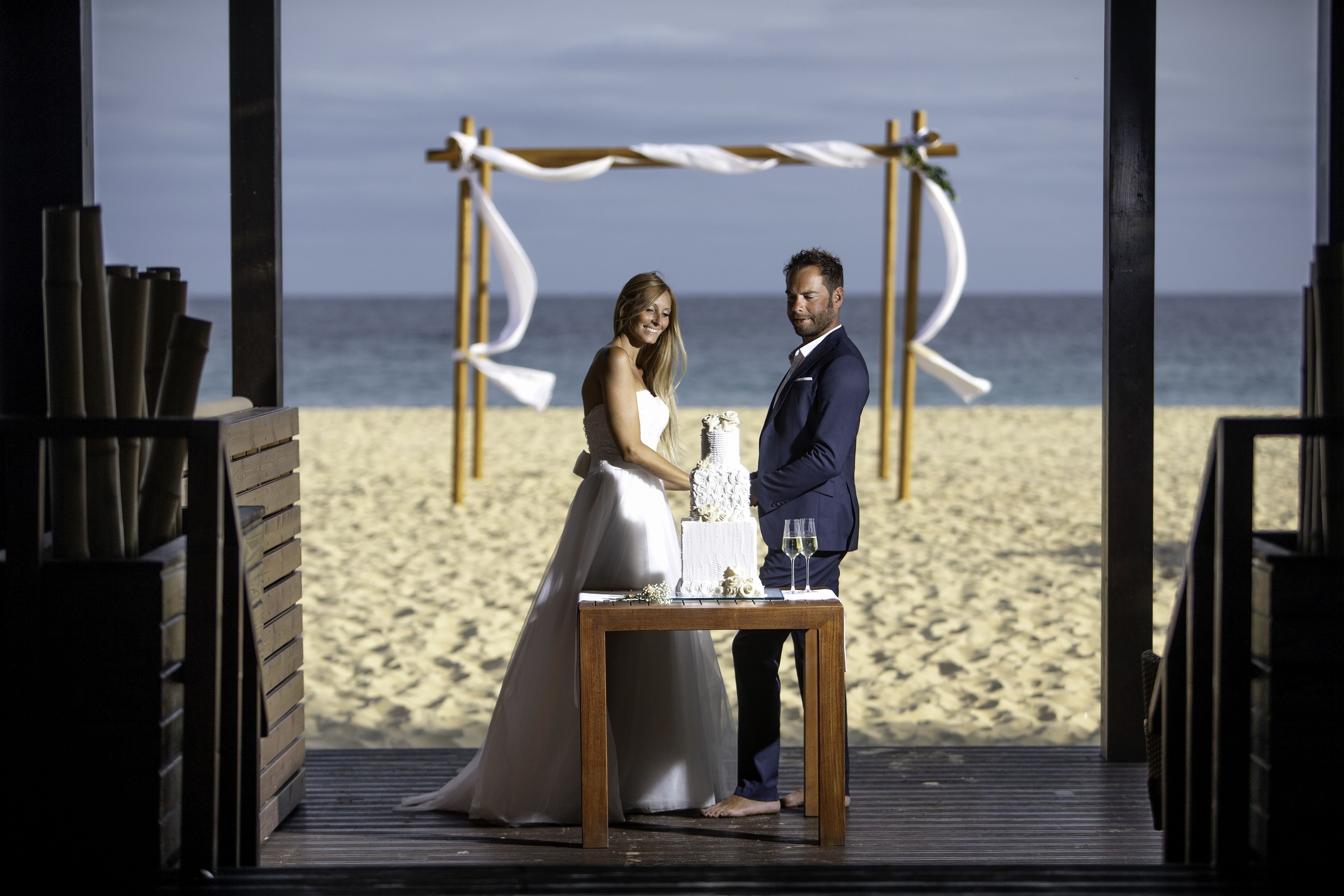 A wedding ceremony on a wooden deck with a view of the beach and ocean.