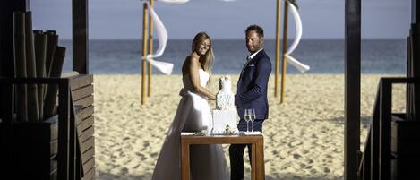 A wedding ceremony on a wooden deck with a view of the beach and ocean.