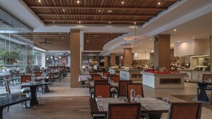 A spacious restaurant with wooden ceiling beams, large windows, and a central island with a buffet. - Hilton Cabo Verde Sal Resort (Sal)