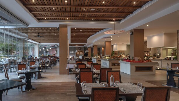 A spacious restaurant with wooden ceiling beams, large windows, and a central island with a buffet. - Hilton Cabo Verde Sal Resort (Sal)