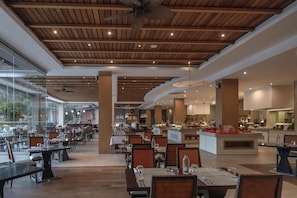 A spacious restaurant with wooden ceiling beams, large windows, and a central island with a buffet. - Hilton Cabo Verde Sal Resort (Sal)