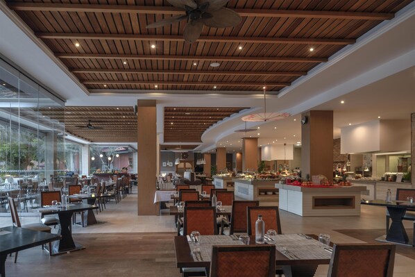 A spacious restaurant with wooden ceiling beams, large windows, and a central island with a buffet. - Hilton Cabo Verde Sal Resort (Sal)