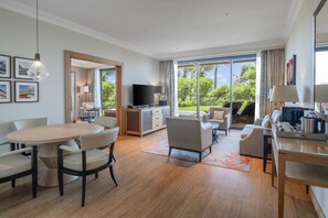A modern hotel room with a dining area, a sofa, a TV, and a large sliding glass door to the outdoors. - Hilton Cabo Verde Sal Resort (Sal)