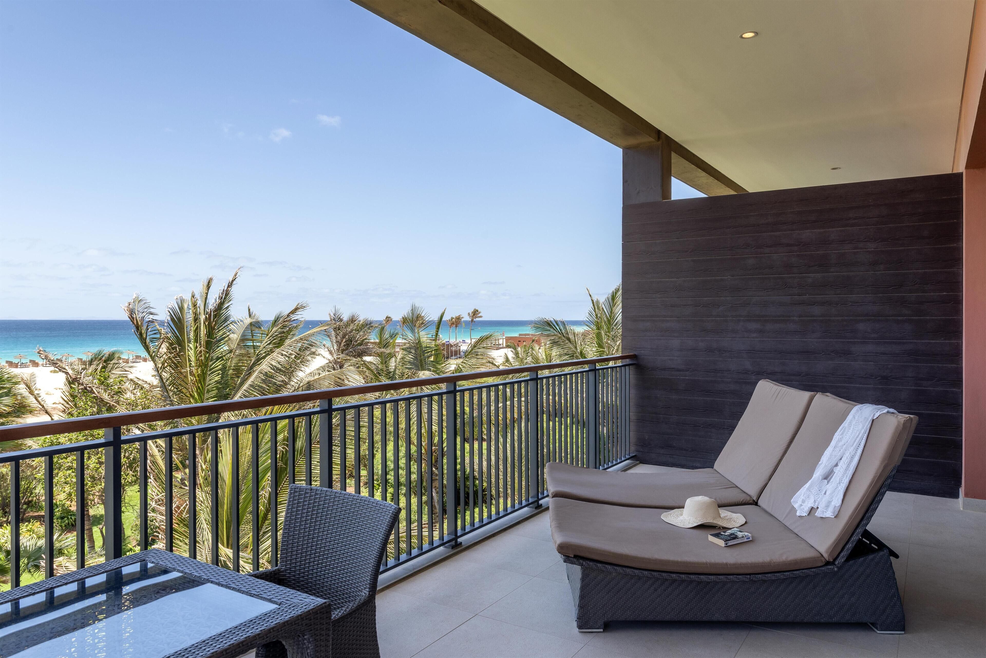 Un balcon avec vue sur l’océan, un canapé et une table.