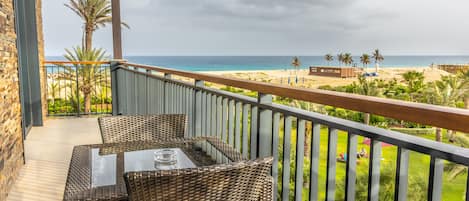 Un balcón con mobiliario de mimbre con vistas a una playa.