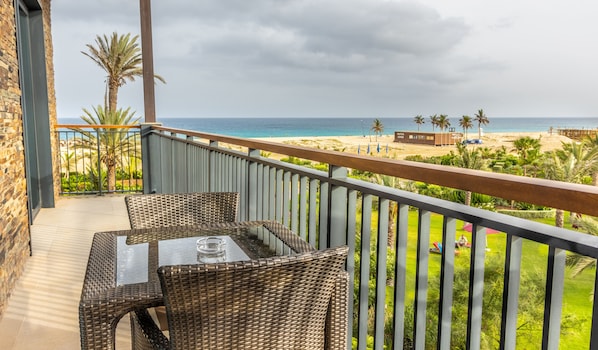 A balcony with wicker furniture overlooking a beach.