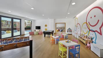 A children's play area with a pool table, colorful chairs, and a large wall mural.