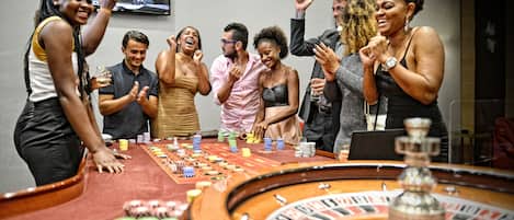 Un grupo de personas alrededor de una mesa de casino con fichas y una ruleta.
