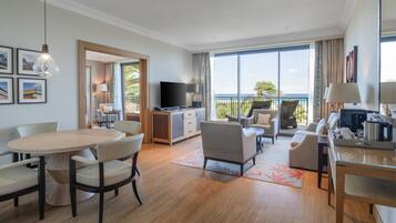 Una camera d'albergo moderna con angolo ristoro, zona living con divano e poltrone, televisione e balcone con vista.