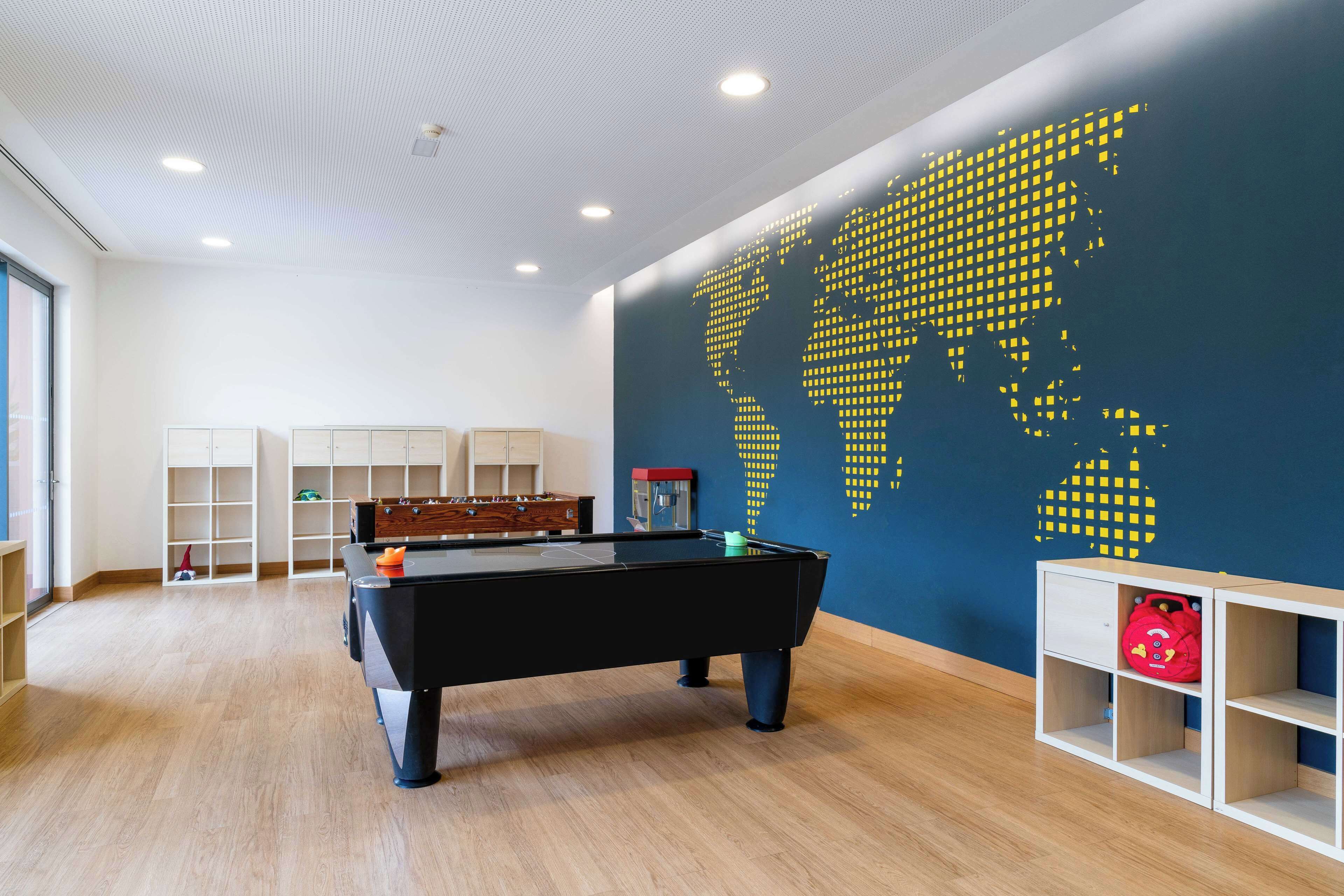 Ein Zimmer mit Billardtisch, Regalen und einer Weltkarte an der Wand.
