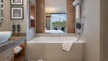 Un baño moderno con una bañera grande, un lavabo y un espejo. Se ve un balcón a través de la ventana.