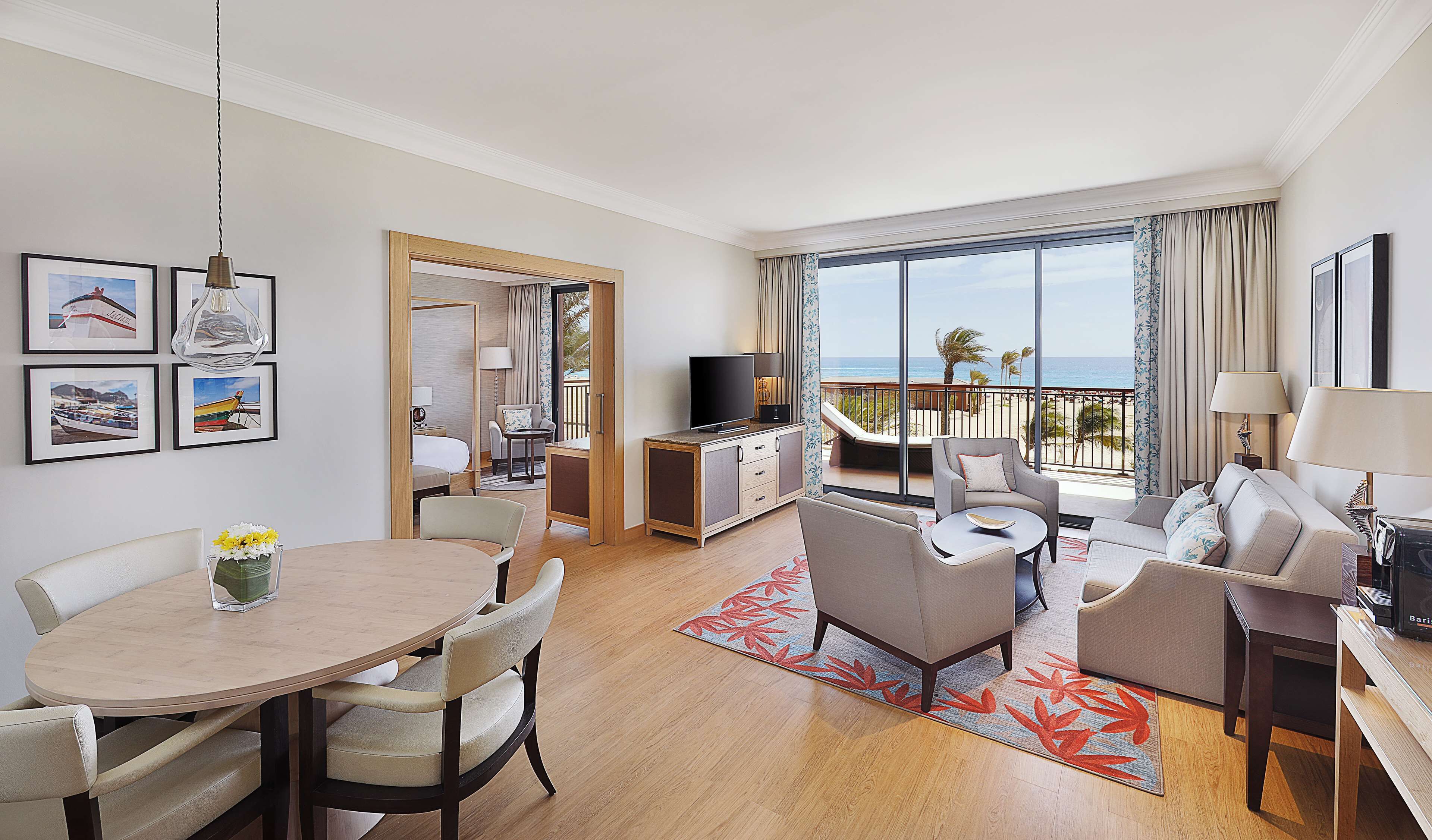 Una habitación de hotel con balcón, comedor, sala de estar y dormitorio.