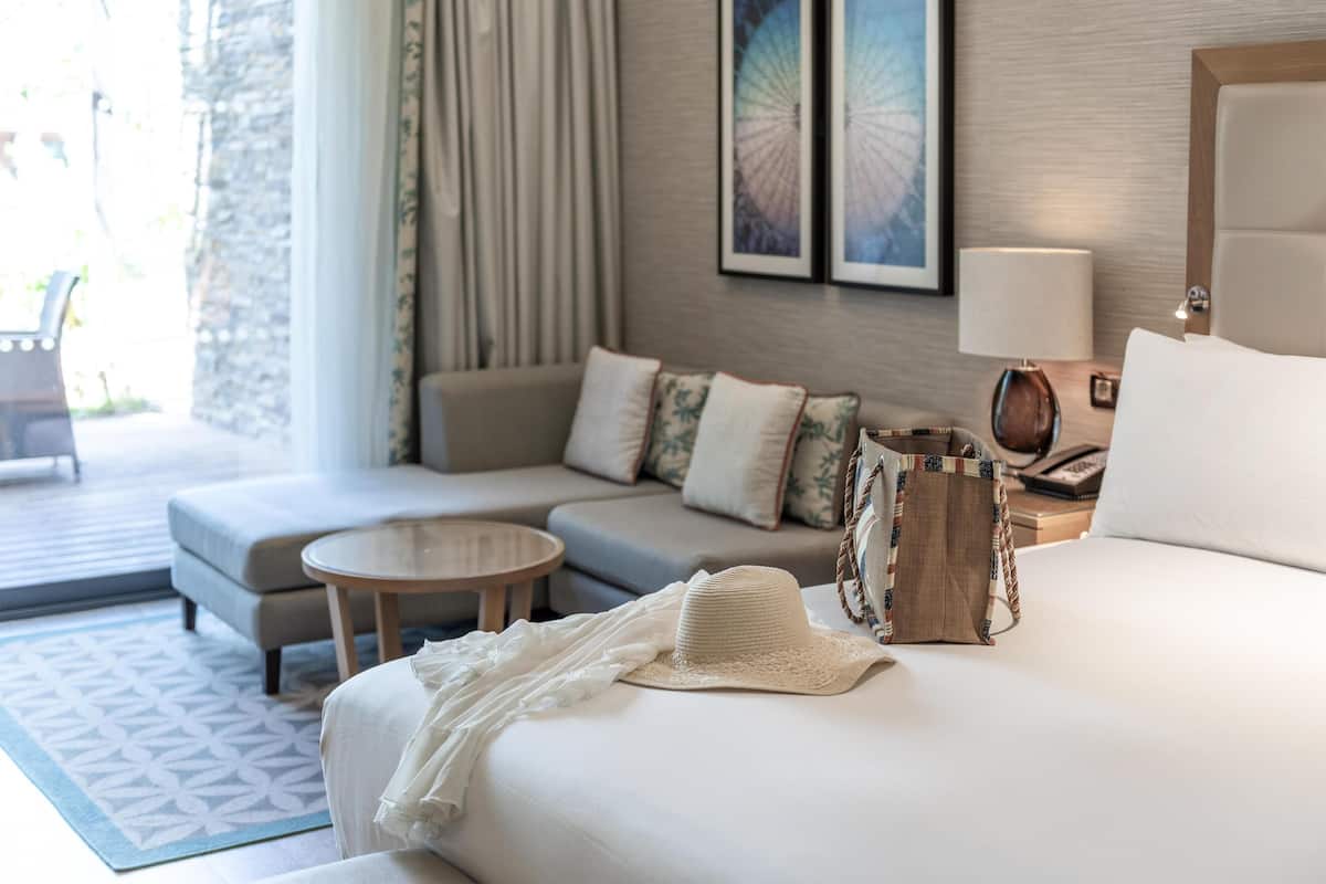 A hotel room with a bed, a sofa, a round table, and a lamp.