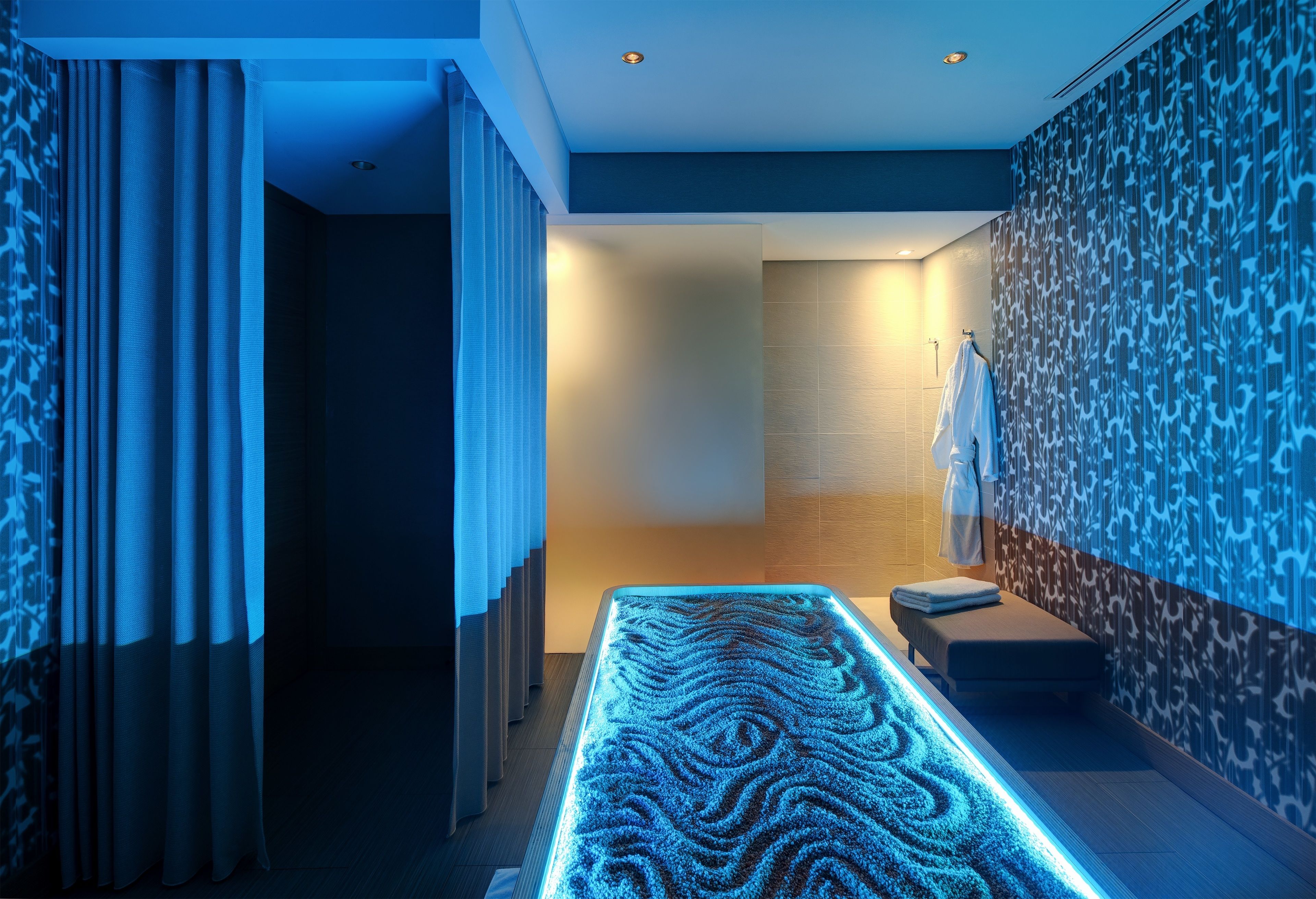 A modern spa area with a heated floor, a bench, and a towel rack.