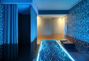 A modern spa area with a heated floor, a bench, and a towel rack. - Hilton Cabo Verde Sal Resort (Sal)