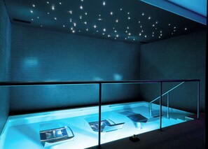 A modern interior with a glass floor, metal railings, and a ceiling with star-like lights. - Hilton Cabo Verde Sal Resort (Sal)