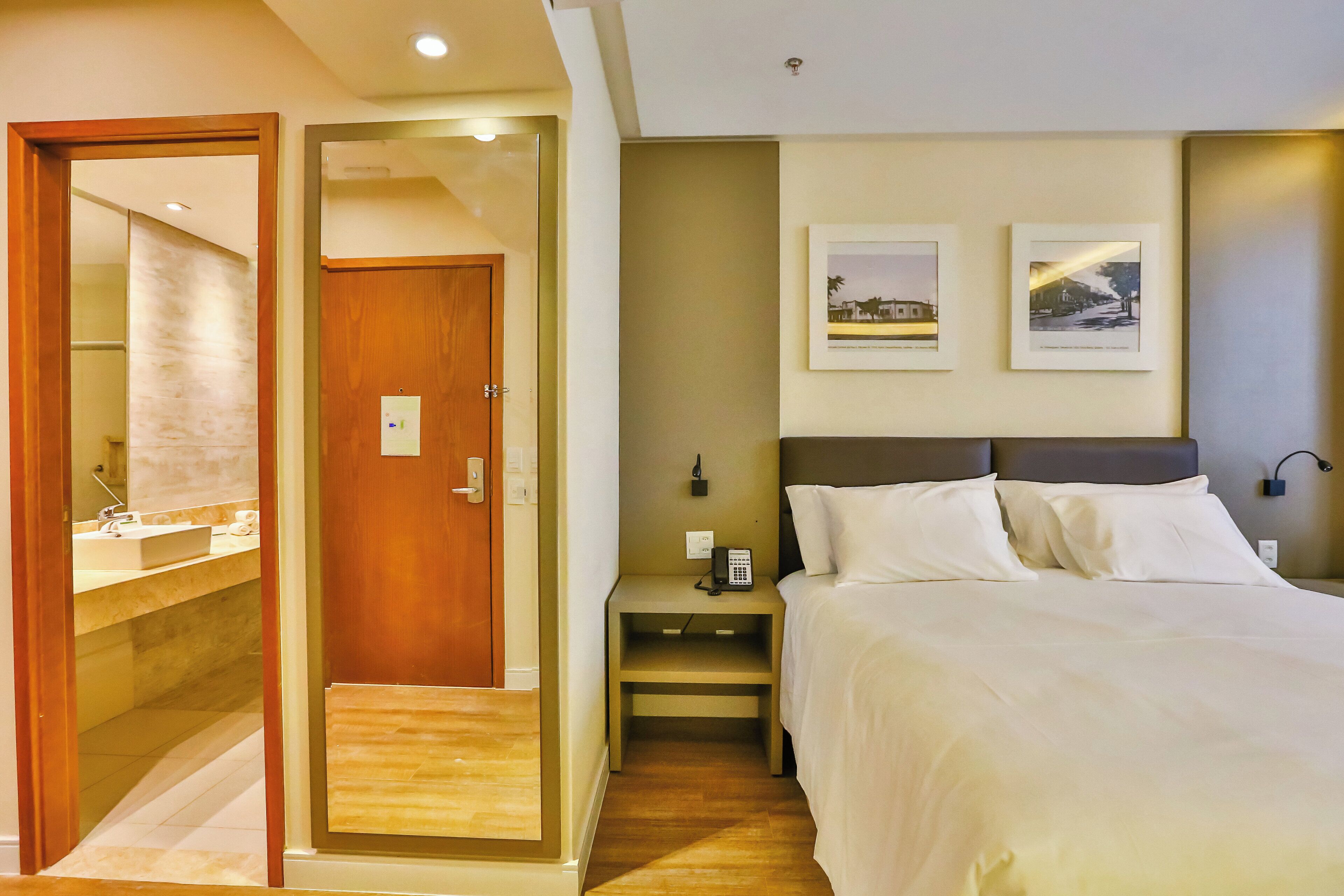 Een hotelkamer met een bed, nachtkastje en een spiegel.