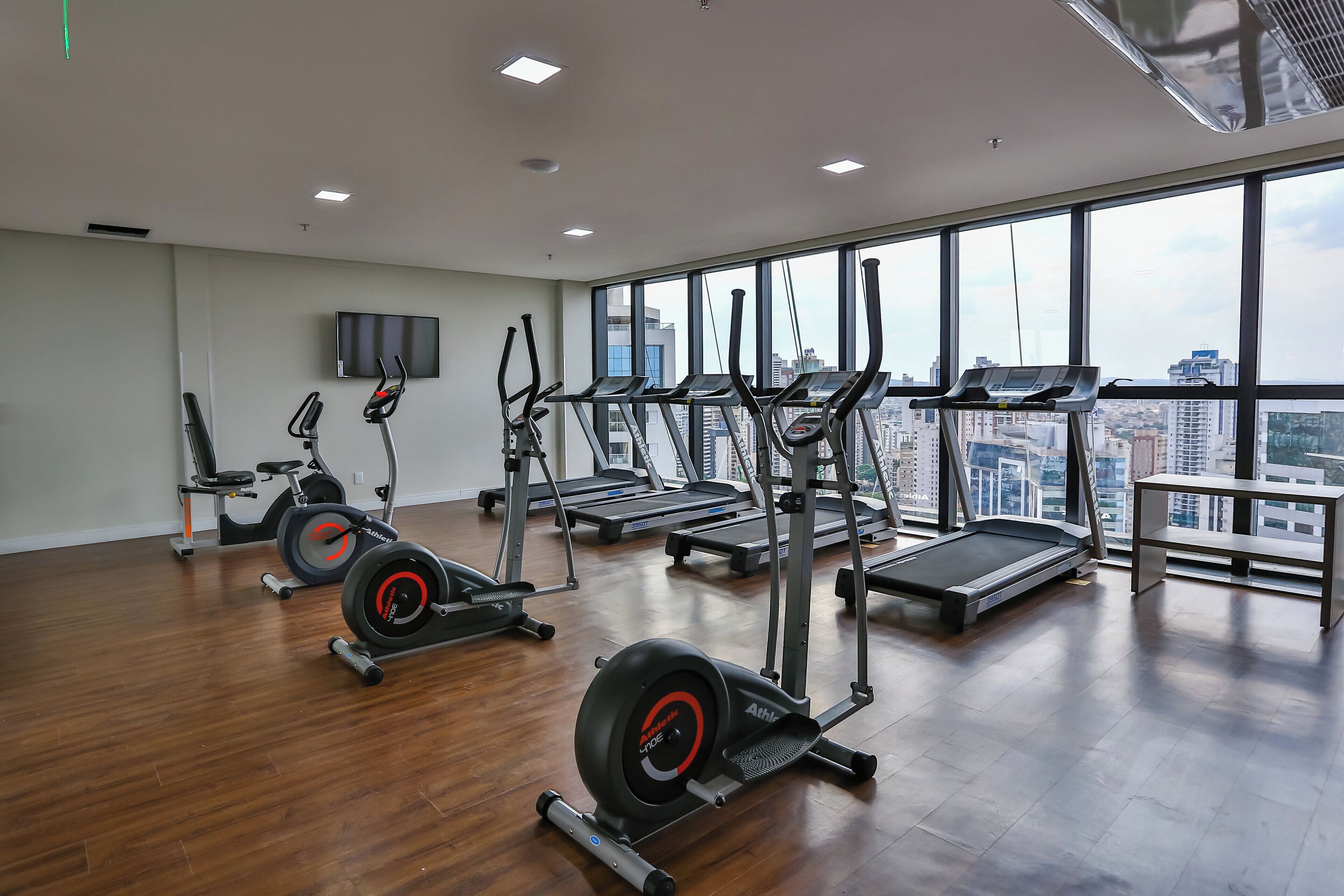 Un gimnasio con cintas de correr, elípticas y una banca.