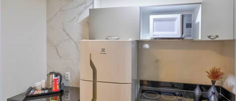 A compact kitchen with a refrigerator, microwave, and stove.