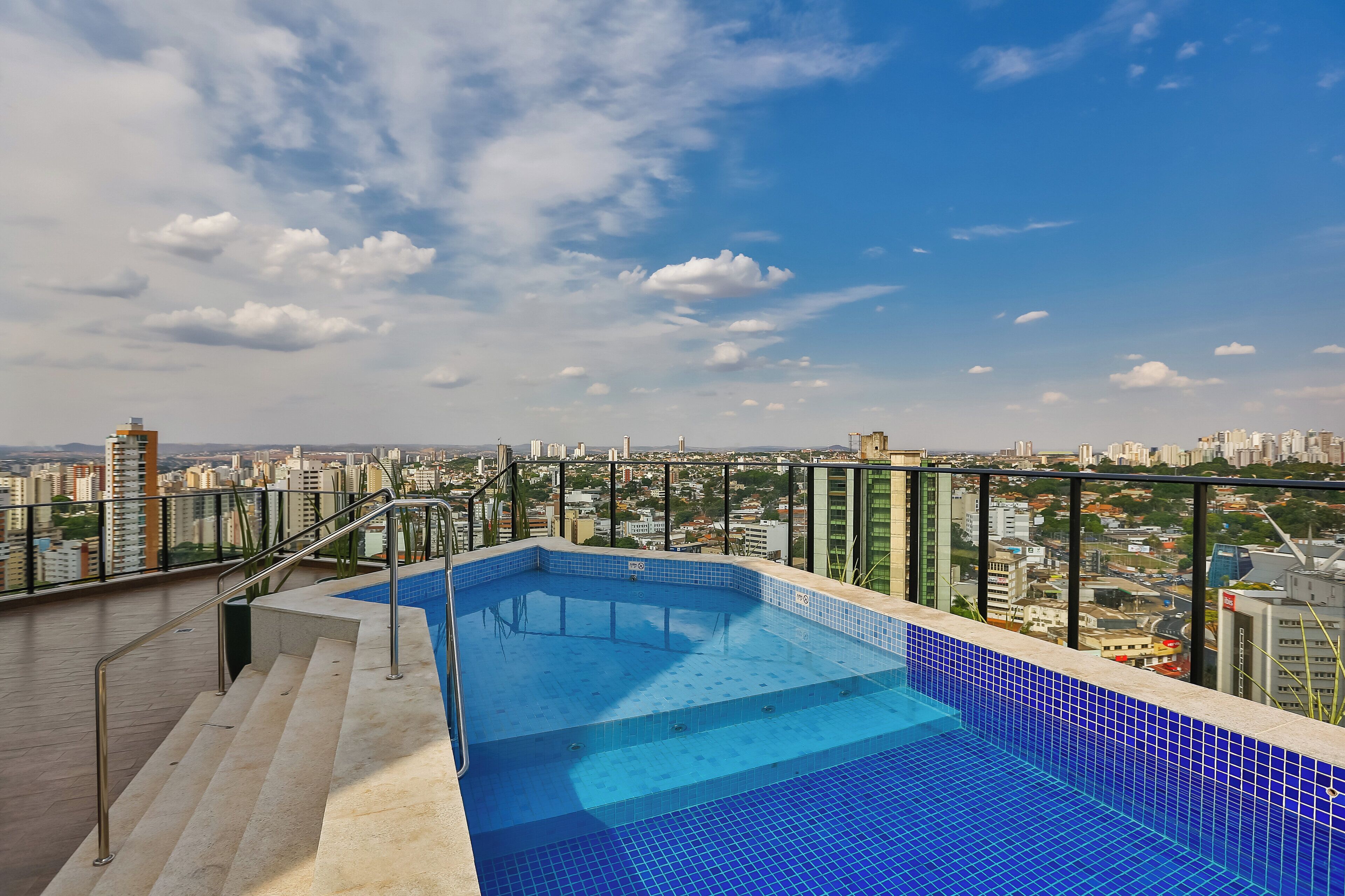 A rooftop pool with a city view, surrounded by a metal railing.