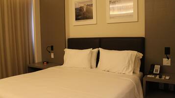 Una camera d'albergo con un letto, comodini, un telefono e una sveglia.