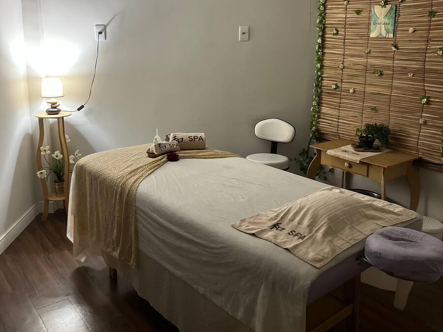 A neatly arranged bedroom with a bed, bedside table, lamp, and a wall-mounted decorative panel.
