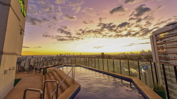 Une piscine sur le toit offrant une vue sur la ville au coucher du soleil.