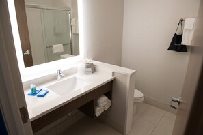 Ein modernes Badezimmer mit einem großen Spiegel, zwei Waschbecken, einer Toilette und einem Handtuchhalter.