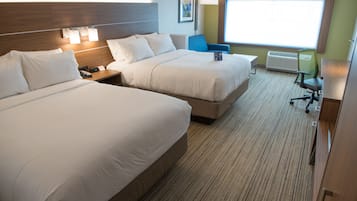 Een hotelkamer met twee bedden, een bureau, een stoel en een groot raam.