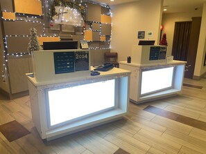Ein Hotel-Empfangsbereich mit zwei beleuchteten Empfangstheken, einem Weihnachtsbaum und festlicher Dekoration.