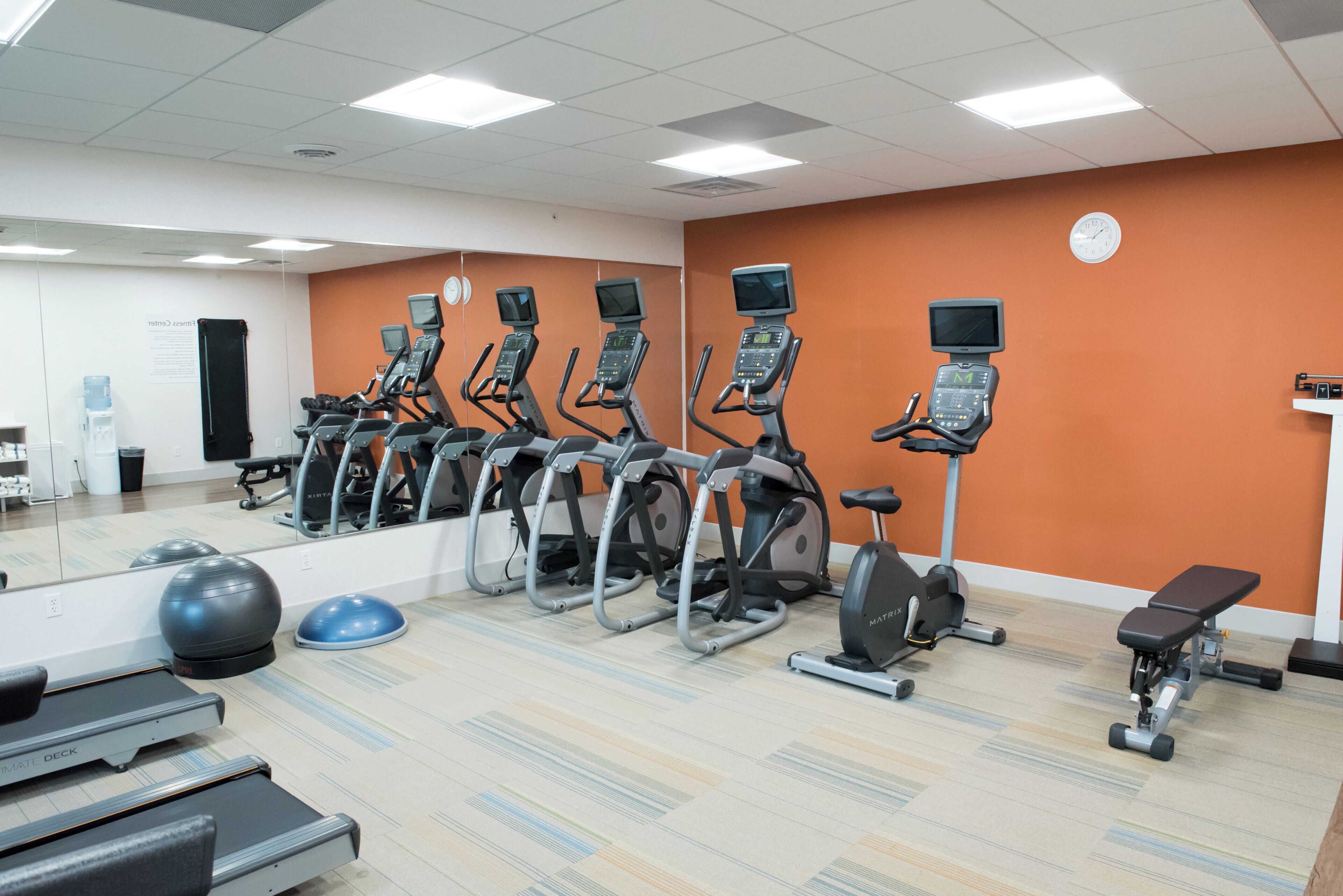 A gym with multiple treadmills, stationary bikes, and exercise balls.