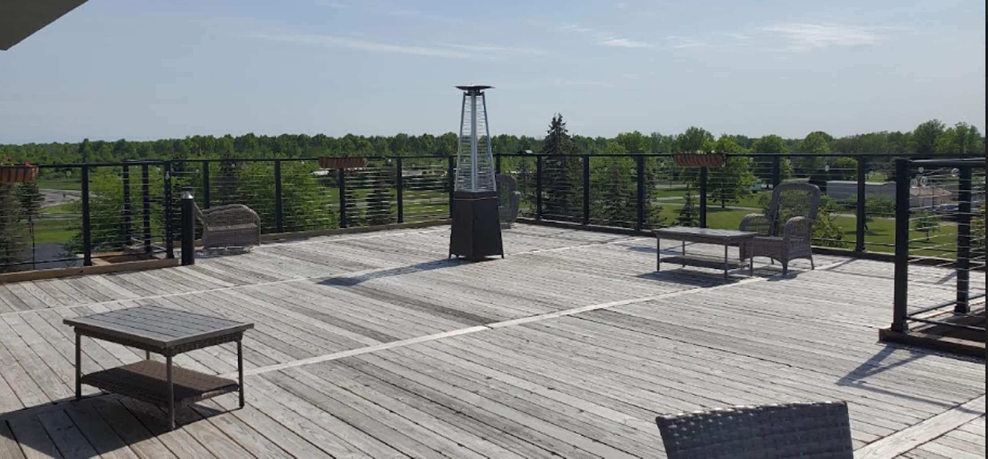 A wooden deck with a metal railing, a table, and two chairs.