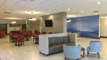 A hotel lobby with a reception desk, seating area, and a large wall mural.