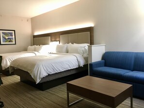 A hotel room with two beds, a blue sofa, and a wooden coffee table. - Holiday Inn Express Grand Island - Niagara Falls by IHG (Grand Island)