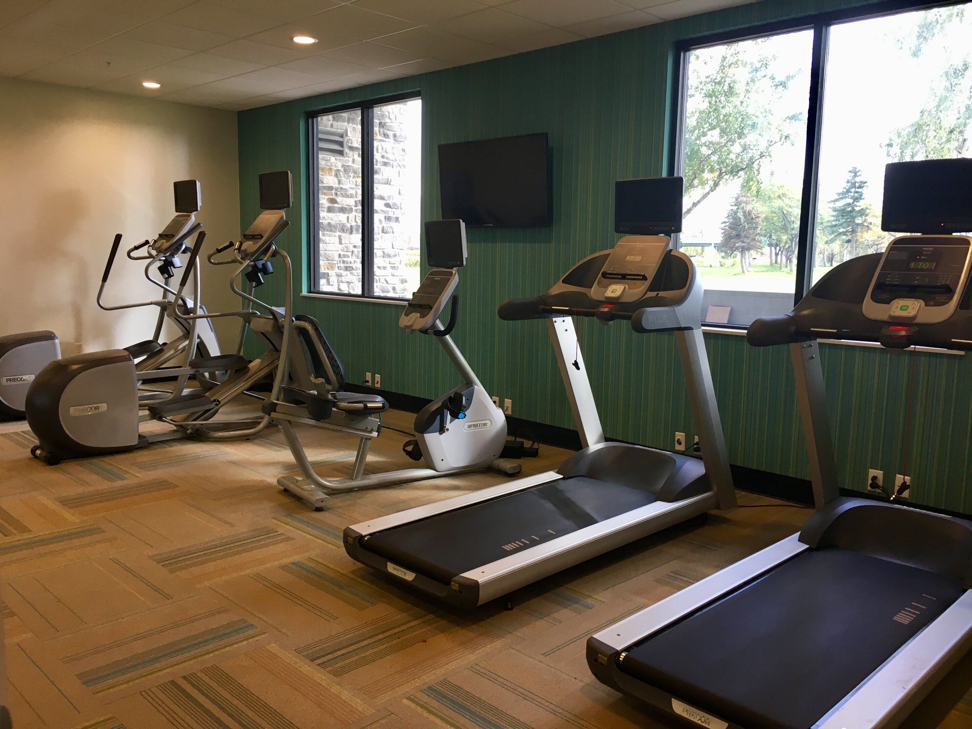 Ein Fitnessstudio mit Laufbändern, Crosstrainern und Ergometer.