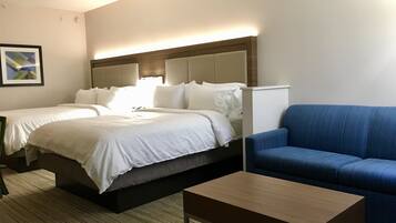A hotel room with a bed, a blue sofa, a wooden coffee table, and a wall-mounted lamp.