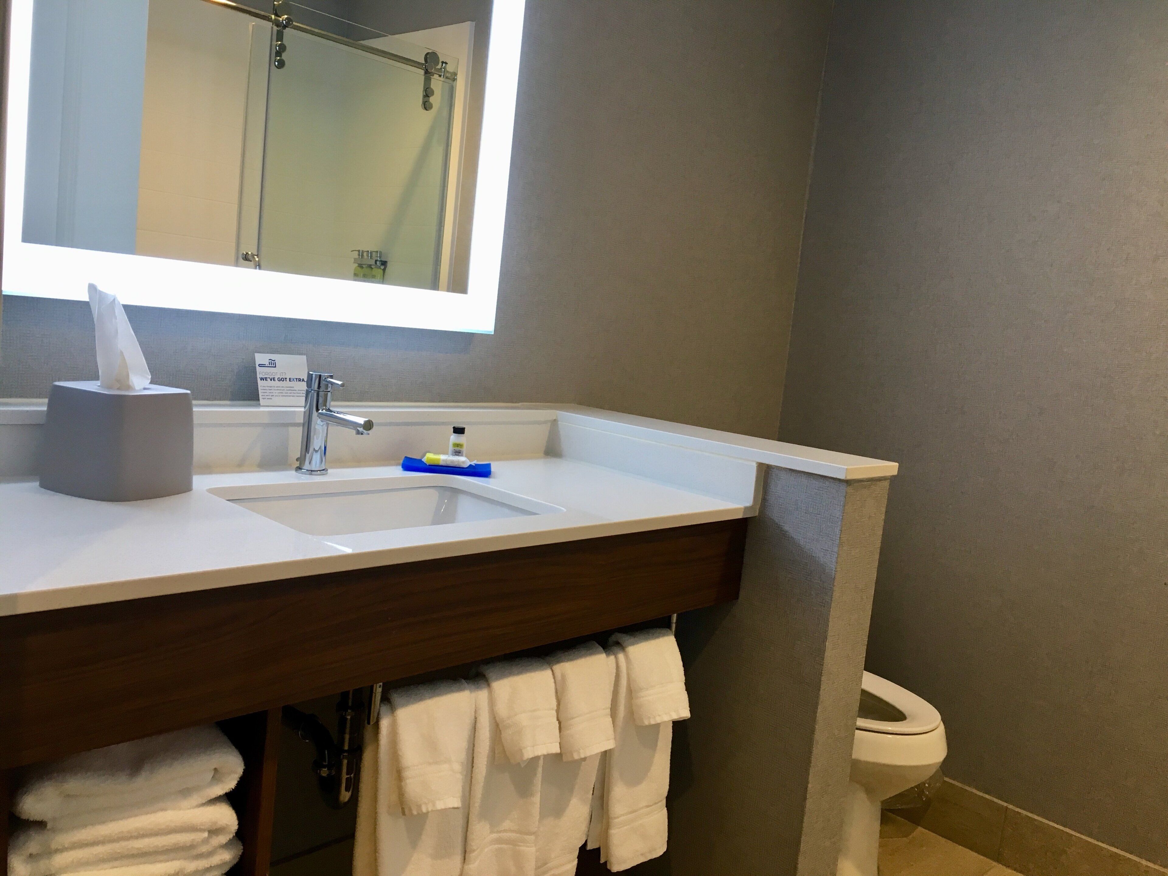 Une salle de bain équipée d’un lavabo, d’un miroir, d’un porte-serviettes et de toilettes.
