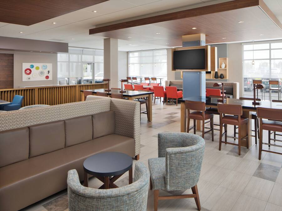 A modern dining area with a mix of seating options including a sofa, chairs, and tables.