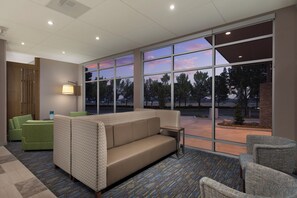 A modern waiting area with a sofa, chairs, and a lamp. - Holiday Inn Express & Suites Portland Airport - Cascade Stn by IHG (Portland)