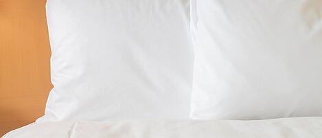 A white pillow on a bed with a wooden headboard.