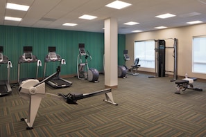 Un gimnasio con cintas de correr, elípticas y máquinas de pesas.