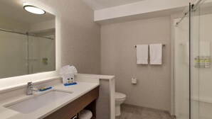 A modern bathroom with a large mirror, a sink, a toilet, and a glass shower enclosure. - Holiday Inn Express & Suites Portland Airport - Cascade Stn by IHG (Portland)