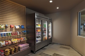A snack and beverage display area with refrigerated sections and shelves stocked with various products. - Holiday Inn Express & Suites Portland Airport - Cascade Stn by IHG (Portland)