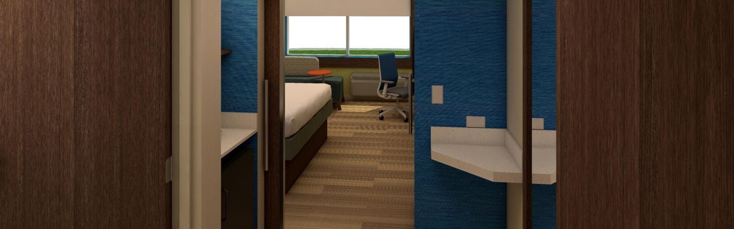 A hotel room with a bed, a desk, a chair, and a window.