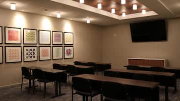 A conference room with tables and chairs, a flat-screen TV, and framed artwork on the wall.