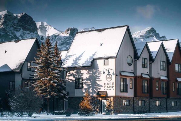 A hotel with a mountain backdrop, featuring a sign that reads "BASE CAMP RESORTS."