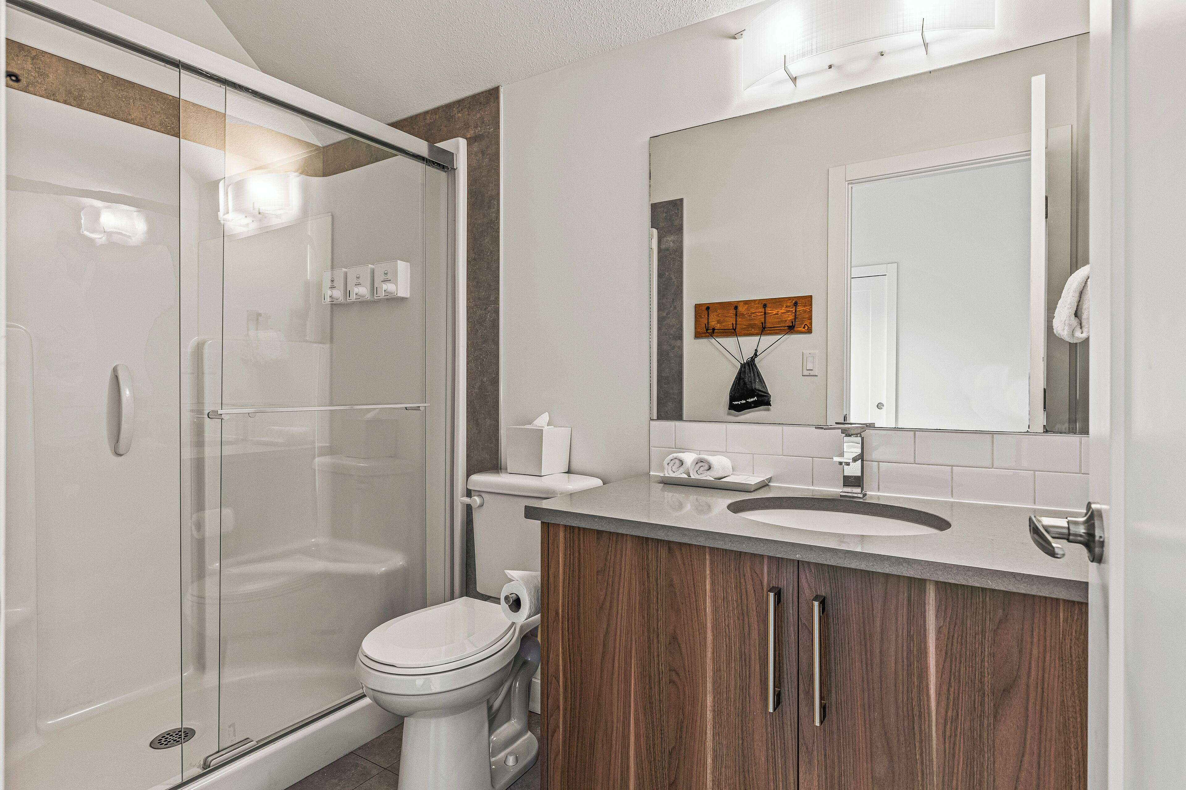 Une salle de bain moderne avec une douche à parois de verre, des toilettes, un lavabo et des meubles en bois.