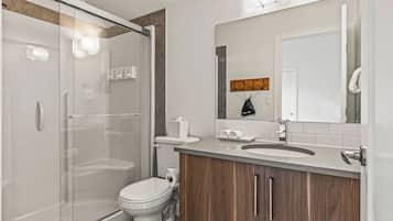Une salle de bain moderne avec une douche à parois de verre, des toilettes, un lavabo et des meubles en bois.