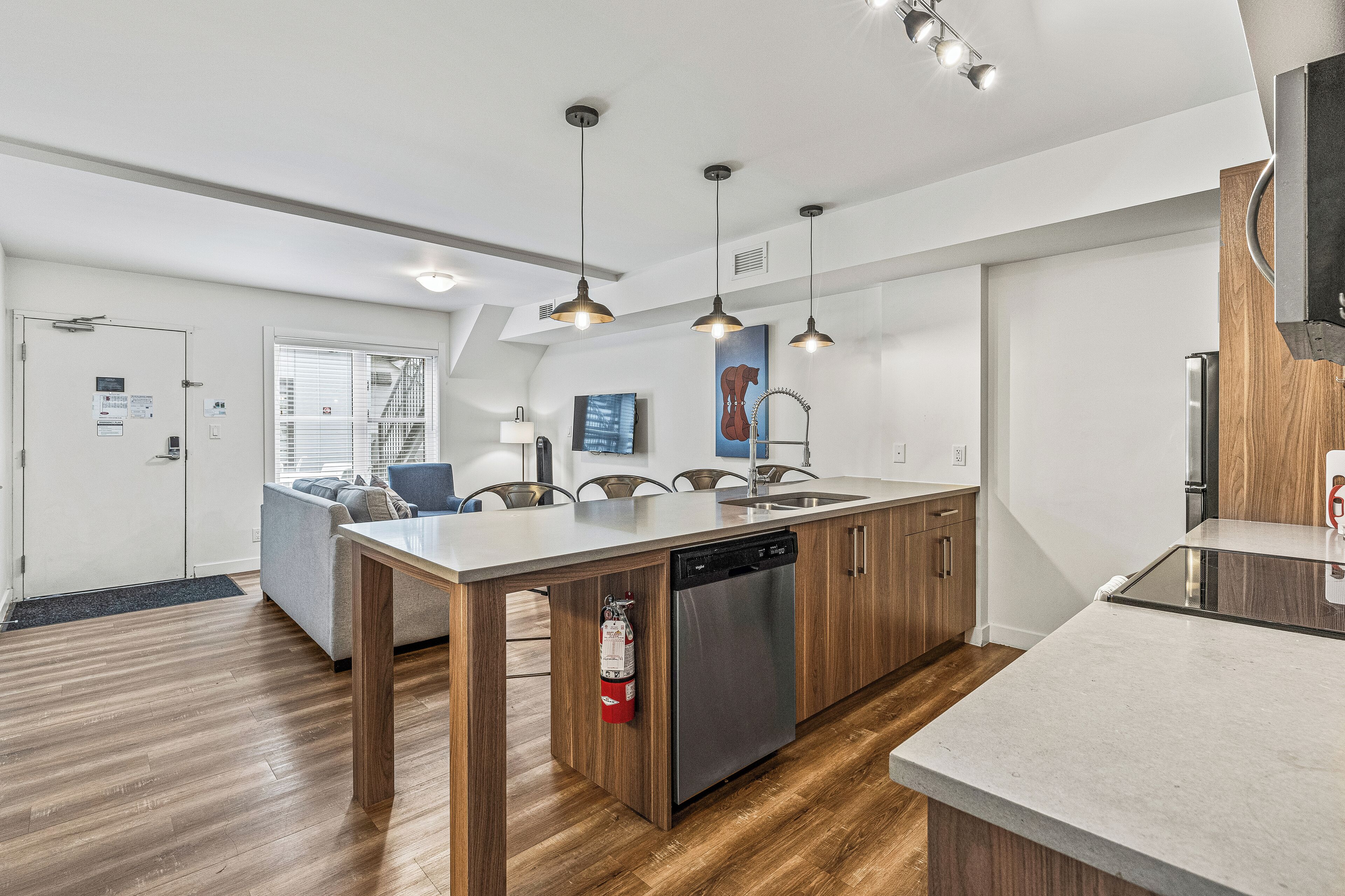 A modern kitchen with a dishwasher, wooden cabinets, and pendant lighting.