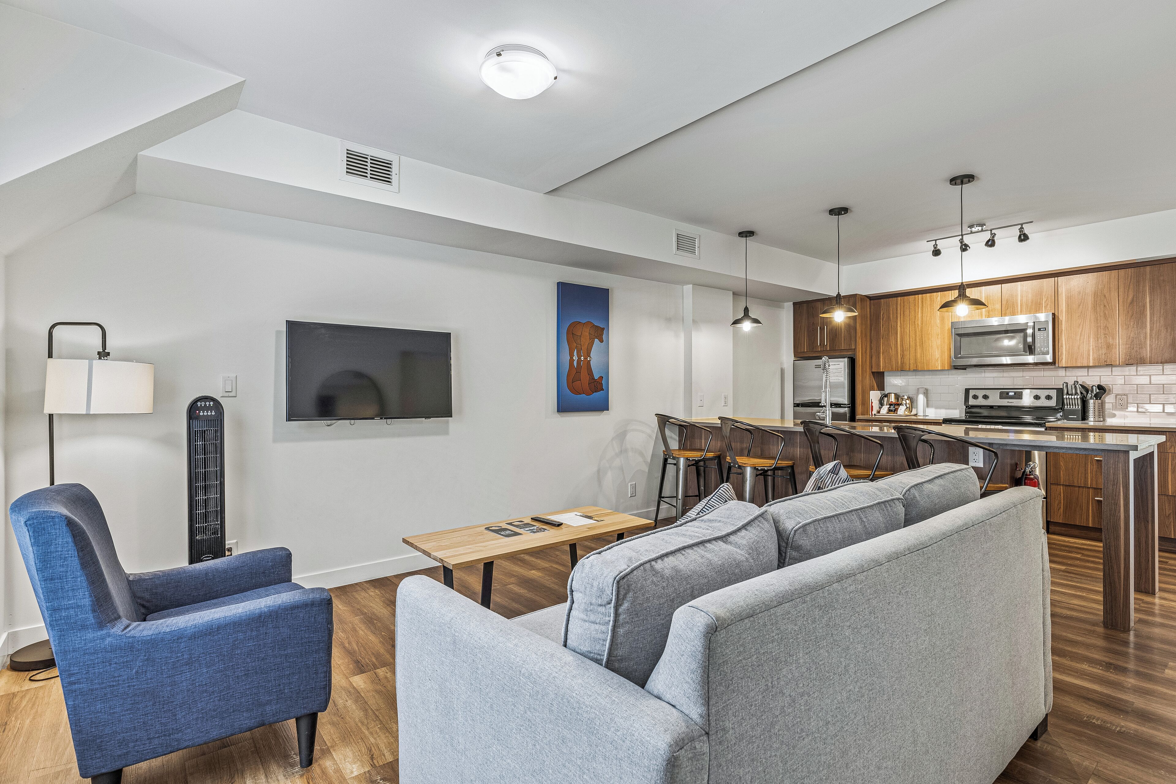 A modern kitchen with wooden cabinets, a built-in microwave, and a dining area with a table and chairs.